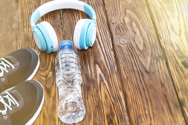 Équipement sportif. Baskets, eau et écouteurs sur fond en bois — Photo