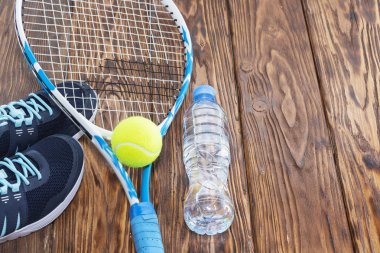 Tenis karanlık bir arka plan üzerinde. spor ayakkabı, roket, top, şişe suyu.