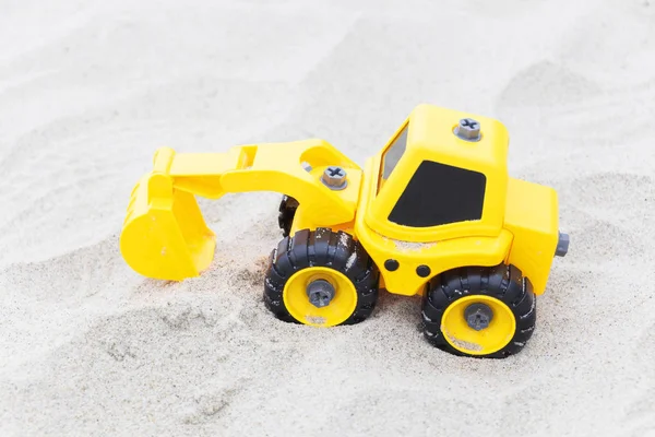 Gelbes Baggerspielzeug im Sand, am Strand. Spielzeug für Jungen — Stockfoto