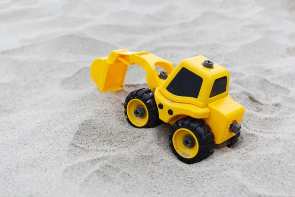 Gelbes Baggerspielzeug im Sand, am Strand. Spielzeug für Jungen — Stockfoto