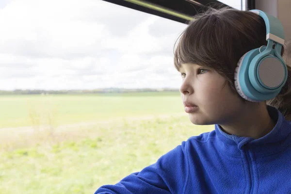 Flickan tittar ut genom fönstret på tåget och lyssnar på musik i hörlurar. — Stockfoto