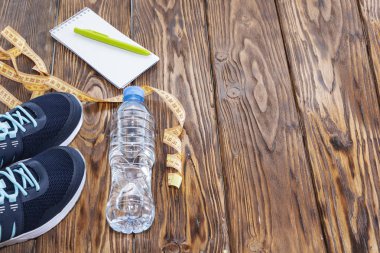 Sağlıklı yaşam ve spor arka plan. Spor ayakkabı, not defteri ve kalem ve su şişesi boşaltmak, TOPVIEW ahşap zemin üzerine.