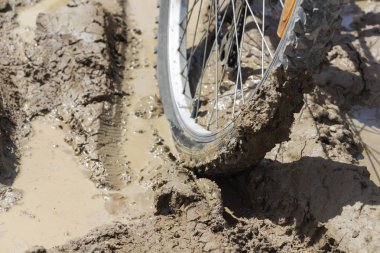 Bisiklet tekerleği çamura saplanmış. Kapat.
