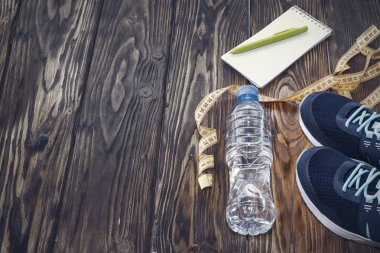 Sağlıklı yaşam ve spor arka plan. Spor ayakkabı, not defteri ve kalem ve su şişesi boşaltmak, TOPVIEW ahşap zemin üzerine.