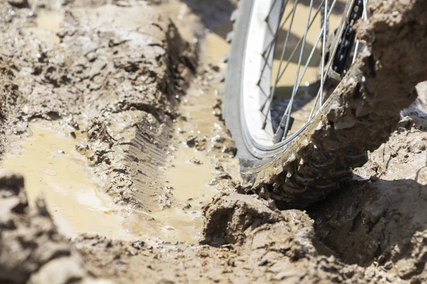 Bisiklet tekerleği çamura saplanmış. Kapat.