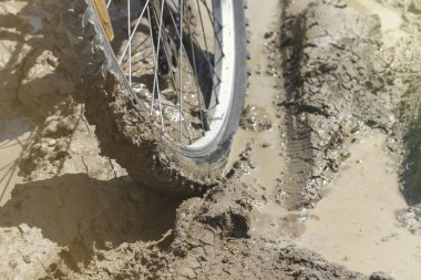 Bisiklet tekerleği çamura saplanmış. Kapat.