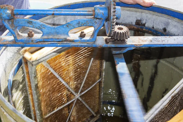 The production of honey from the honeycomb. natural honey dripping. An old honey extractor.