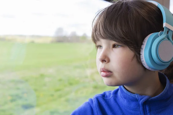 Flickan tittar ut genom fönstret på tåget och lyssnar på musik i hörlurar. — Stockfoto