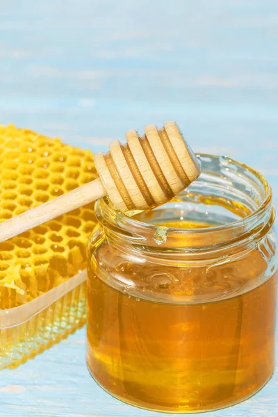 Honey on the background of honeycomb. Honey in a glass jar and honeycomb — Stock Photo, Image