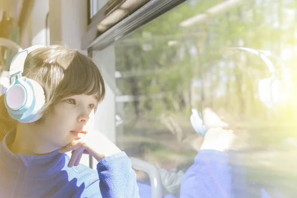 Flickan tittar ut genom fönstret på tåget och lyssnar på musik i hörlurar. — Stockfoto
