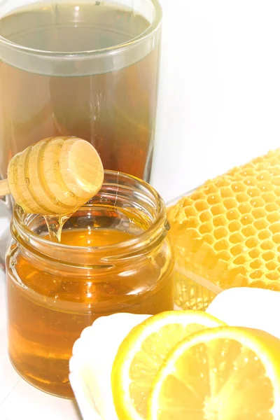 Méz a háttérben a méhsejt. Méz üvegedénybe és méhsejt — Stock Fotó