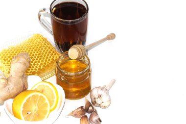 Bal ve sarımsak parçaları bal peteğinin arka planında. Cam kavanozda bal ve bal peteği.