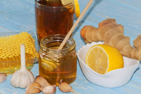 Mel e pedaços de alho no fundo do favo de mel. Mel em um jarro de vidro e favo de mel. — Fotografia de Stock