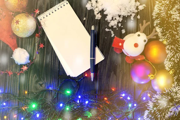 Jouets de Noël sur un fond gris en bois, et un bloc-notes avec un stylo pour écrire. Exécution des désirs . — Photo