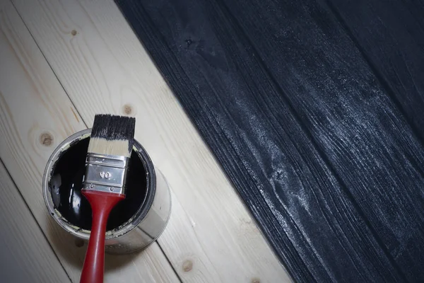 Фарбування дерев'яної дошки чорним кольором. баночка чорної фарби і пензлик . Ліцензійні Стокові Фото