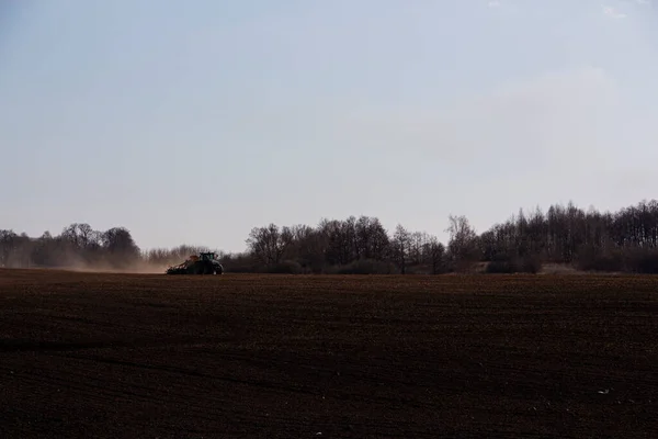 Duży ciągnik z siewnikiem przechodzi przez pole. — Zdjęcie stockowe