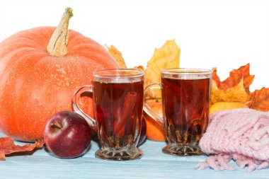 Sonbahar arkaplanı, balkabağı, sarı yapraklı elmalar ve beyaz arka plandaki tahta masada çay..