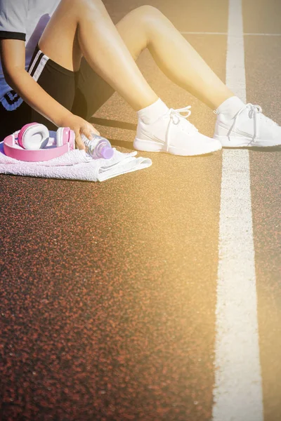 A female runner rests after a hard run on a sports field. Workout. — Stock Photo, Image