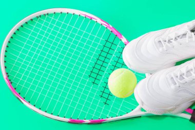 Toplu tenis raketi ve parlak bir arka planda spor ayakkabısı. Stüdyoda Fotoğraflandı.