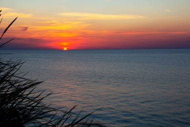 Denizde gün batımı. Güneşin turuncu rengi denizin ufukta gizlidir..