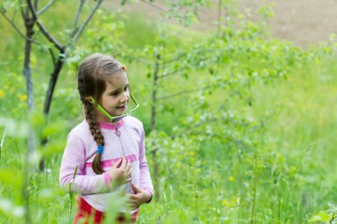 Gözlüklü küçük kız çimenlerde poz veriyor - bahar zamanı