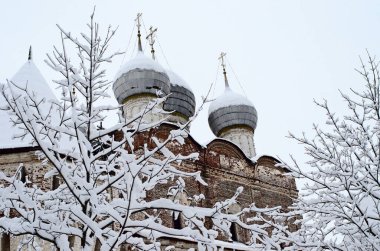 Rus kışı, kilise kulesinin gri gökyüzüne karşı. Ön planda, ağaçların dalları karla kaplıdır.