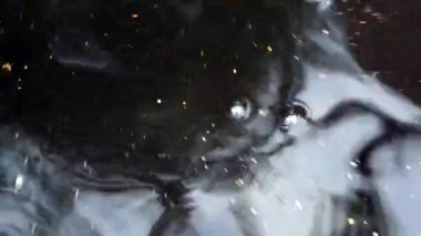 Suyun karanlık hareket eden yüzeyinde ışığın hızlı hareketi