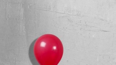 Kırmızı balonlar gri bir duvar üzerinde yükseliyor.