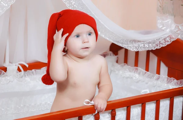 ベッドに笑みを浮かべて赤キャップの小さい赤ん坊 — ストック写真