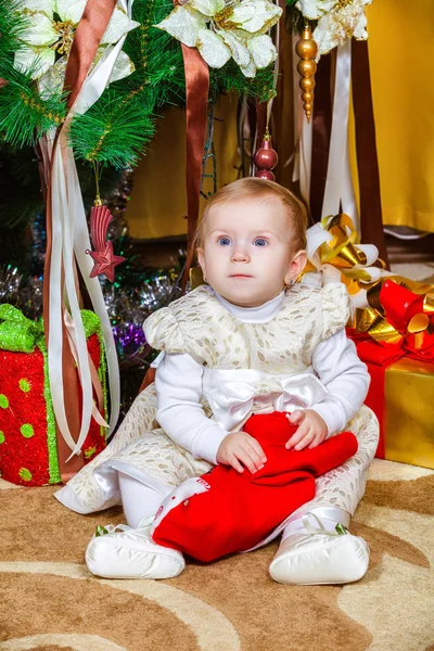 部屋にクリスマス ツリーの下に座っている女の赤ちゃん — ストック写真
