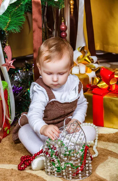 部屋にクリスマス ツリーの下に座っている女の赤ちゃん — ストック写真