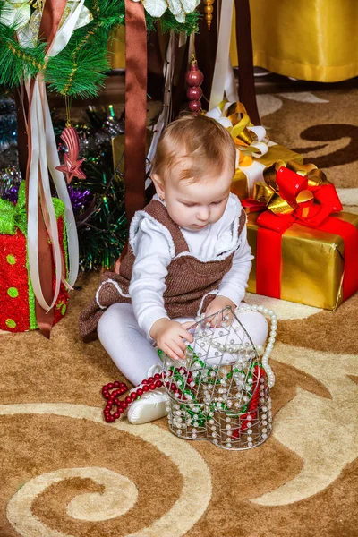 部屋にクリスマス ツリーの下に座っている女の赤ちゃん — ストック写真