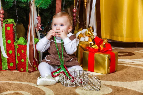 部屋にクリスマス ツリーの下に座っている女の赤ちゃん — ストック写真