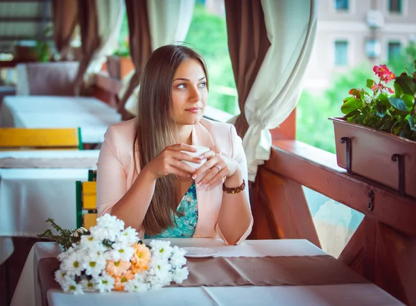 カフェでテーブルに座ってコーヒー カップを保持している若い美しい女性 — ストック写真