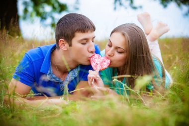 Yeme kırmızı lolipop alanında rahatlatıcı romantik genç çift