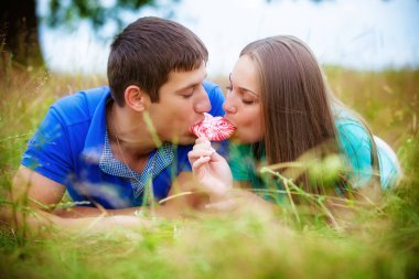 Yeme kırmızı lolipop alanında rahatlatıcı romantik genç çift