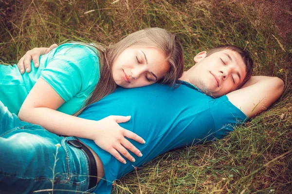 年轻女子抱着她的男人躺在田野上 — 图库照片