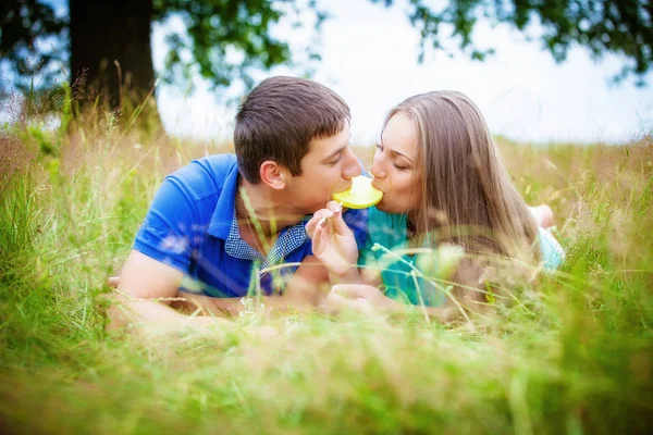 ロマンチックな若いカップル食べる黄色ロリポップは フィールドでのリラックス — ストック写真