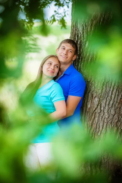 緑豊かな公園の木の近くを抱いて若いカップル — ストック写真
