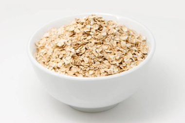 Beyaz yüzey üzerinde çiğ yulaf ezmesi beyaz kase