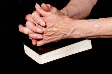 Olgun kadın İncil'in üzerine siyah arka plan üzerinde dua görüntü kırpılmış