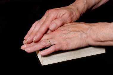 Olgun kadın İncil'in üzerine siyah arka plan üzerinde dua görüntü kırpılmış