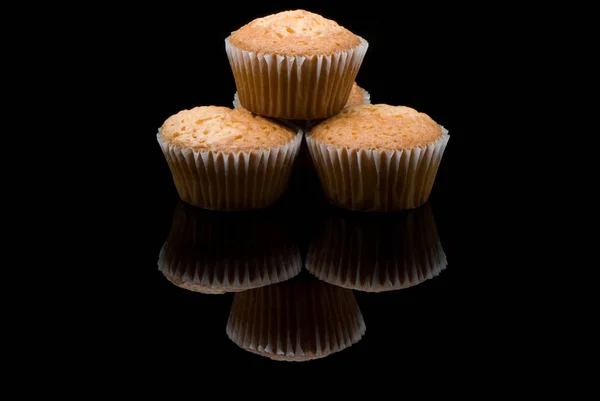 Fyra Nybakade Muffins Reflekterande Svart Yta — Stockfoto