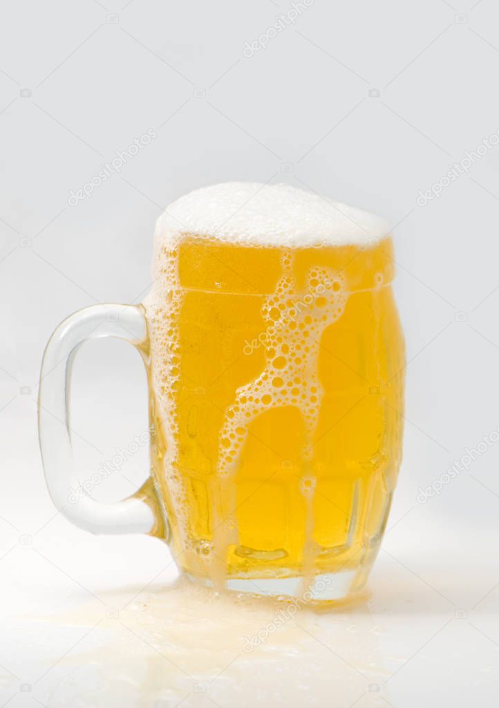 Mug fresh beer with cap of foam on a light background