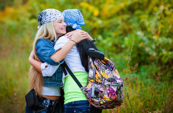 二人の幸せな女性友人バックパック緑豊かな公園に立っているを抱き締める — ストック写真