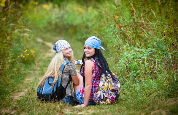 Dos Mujeres Jóvenes Felices Con Mochilas Divirtiéndose Sentadas Carretera Forestal — Foto de Stock