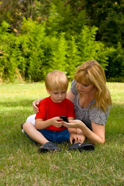 Mãe Filho Deitado Grama Usando Telefone Celular Parque — Fotografia de Stock