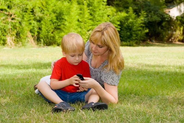 Madre Figlio Sdraiati Sull Erba Utilizzando Telefono Cellulare Nel Parco — Foto Stock