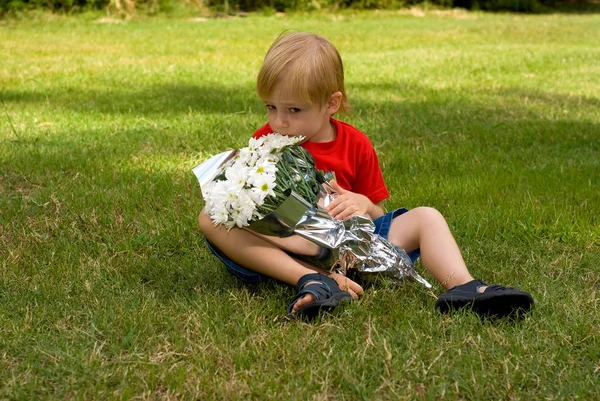 Menino Feliz Segurando Flores Brancas Sentado Grama Verde Parque — Fotografia de Stock