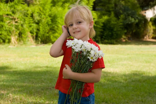 Happy Little Boy Holding White Flowers Talking Phone Standing Green — Stock Photo, Image